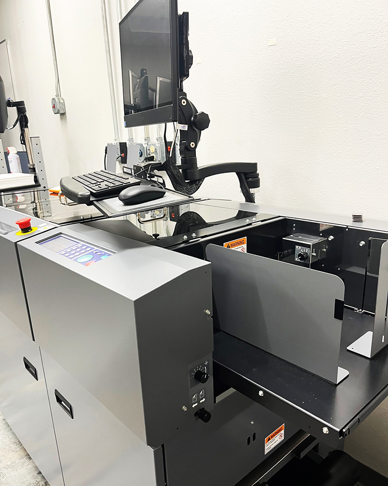 Modern industrial machine with a built-in computer, keyboard, and warning signs. The machine has a sleek design and a professional tone.