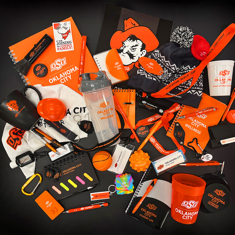 An array of Oklahoma State University-themed items, including notebooks, pens, mugs, and apparel, in vibrant orange and black, displaying school spirit.