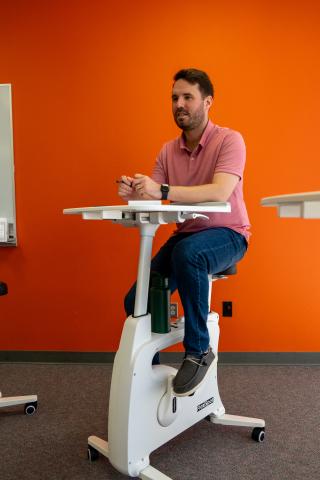 Ross Duren, Health and Wellness Counselor at OSU-OKC, rides an exercise bike during a recent meeting. 